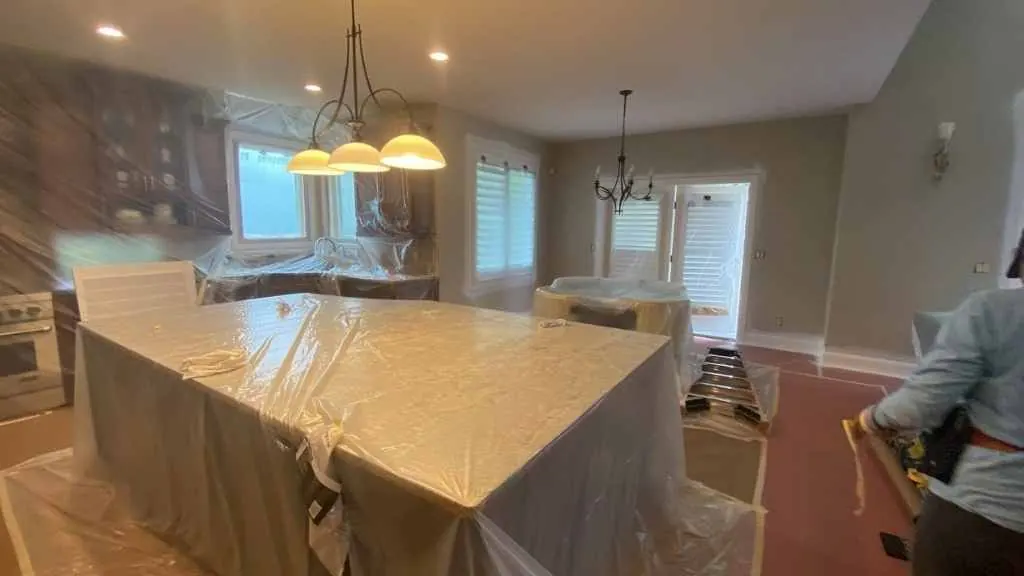 A Kind Home Painting crew member cutting in along a protected baseboard