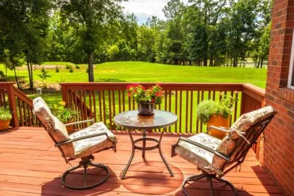 A stained wood deck in sunshine with two chairs