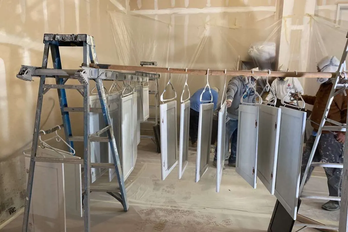 Cabinet doors hung to cure inside a fully masked workspace