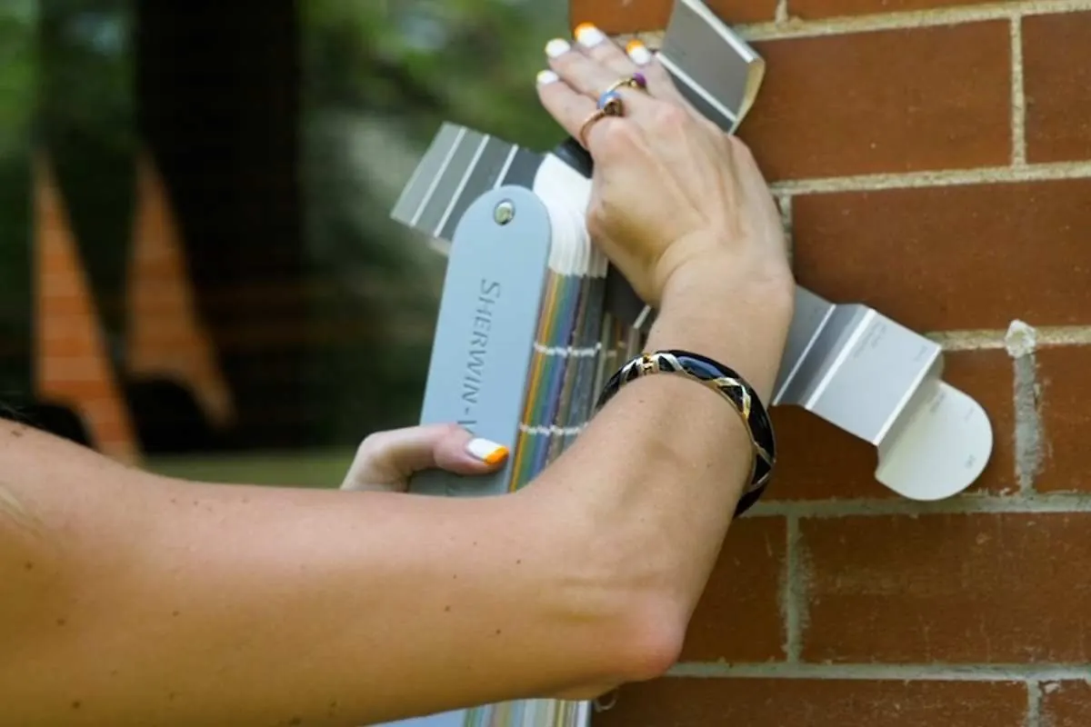 Testing exterior paint swatches against brick