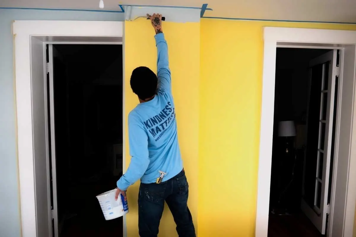 A Kind Home painter cutting in a yellow accent wall